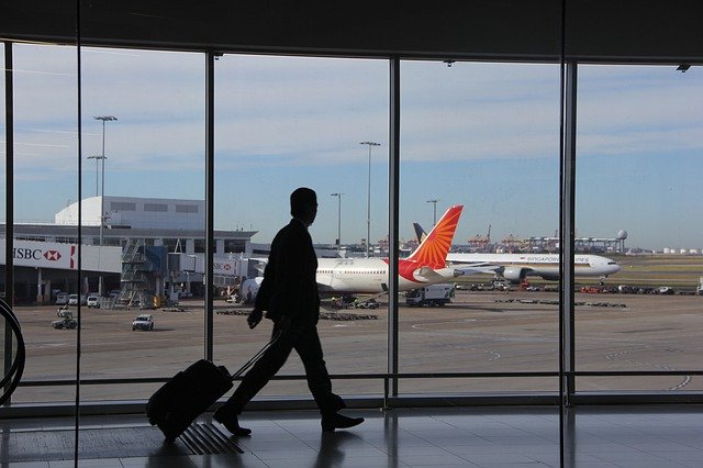 スーツケースを引いて空港を歩いている男性