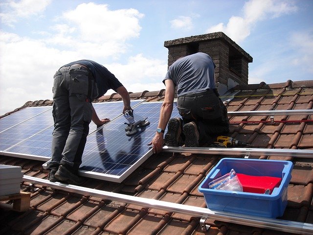 屋根にソーラーパネルを設置している作業員たち
